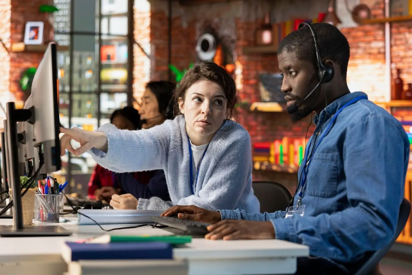 Специалист по онбордингу колл-центра обучает стажёра пользоваться компьютерным программным обеспечением.